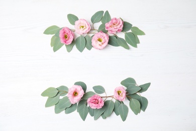 Photo of Fresh eucalyptus leaves with flowers and space for design on white wooden background, flat lay