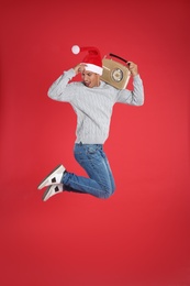 Emotional man with vintage radio jumping on red background. Christmas music