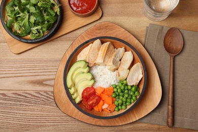 Photo of Boiled rice with vegetables and meat served on wooden table, flat lay