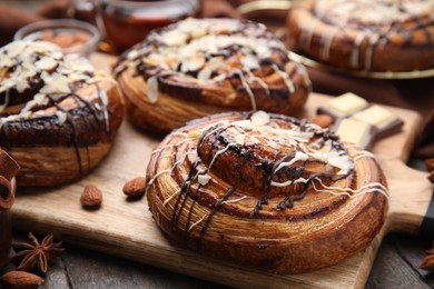 Delicious rolls with toppings and nuts on wooden table, closeup. Sweet buns