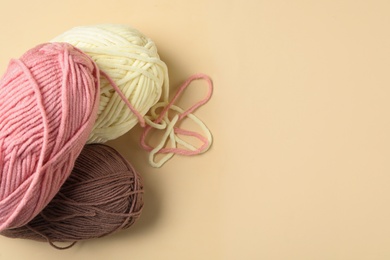 Soft woolen yarns on beige background, flat lay. Space for text