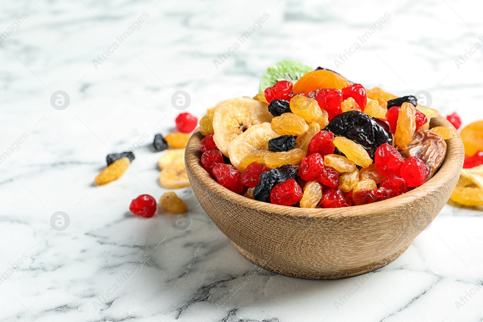 Photo of Bowl with different dried fruits on marble background, space for text. Healthy lifestyle
