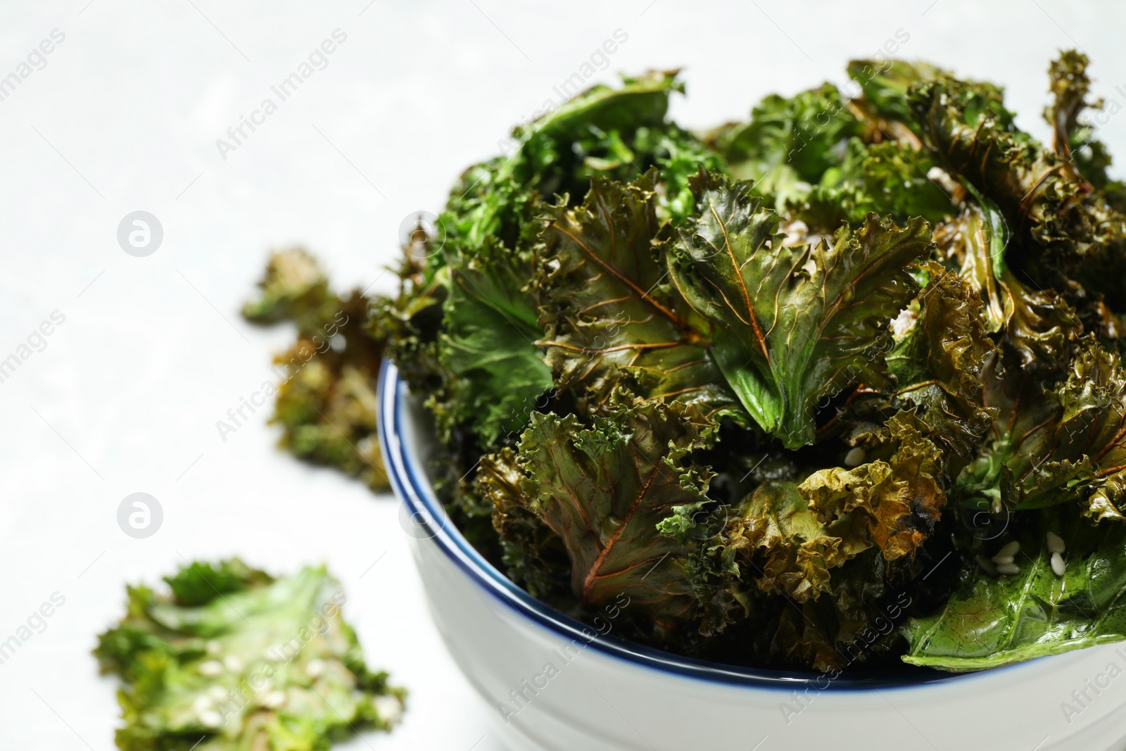 Photo of Tasty baked kale chips in bowl, closeup