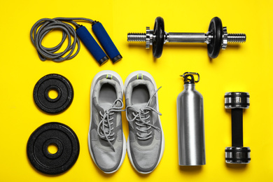 Photo of Gym equipment on yellow background, flat lay