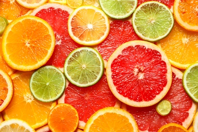 Photo of Slices of fresh citrus fruits as background, top view