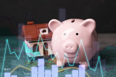 Image of Piggy bank with coins and house model on table. Illustration of financial graphs