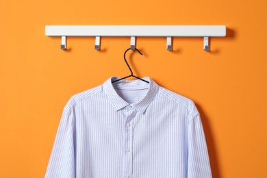 Hanger with striped shirt on orange wall