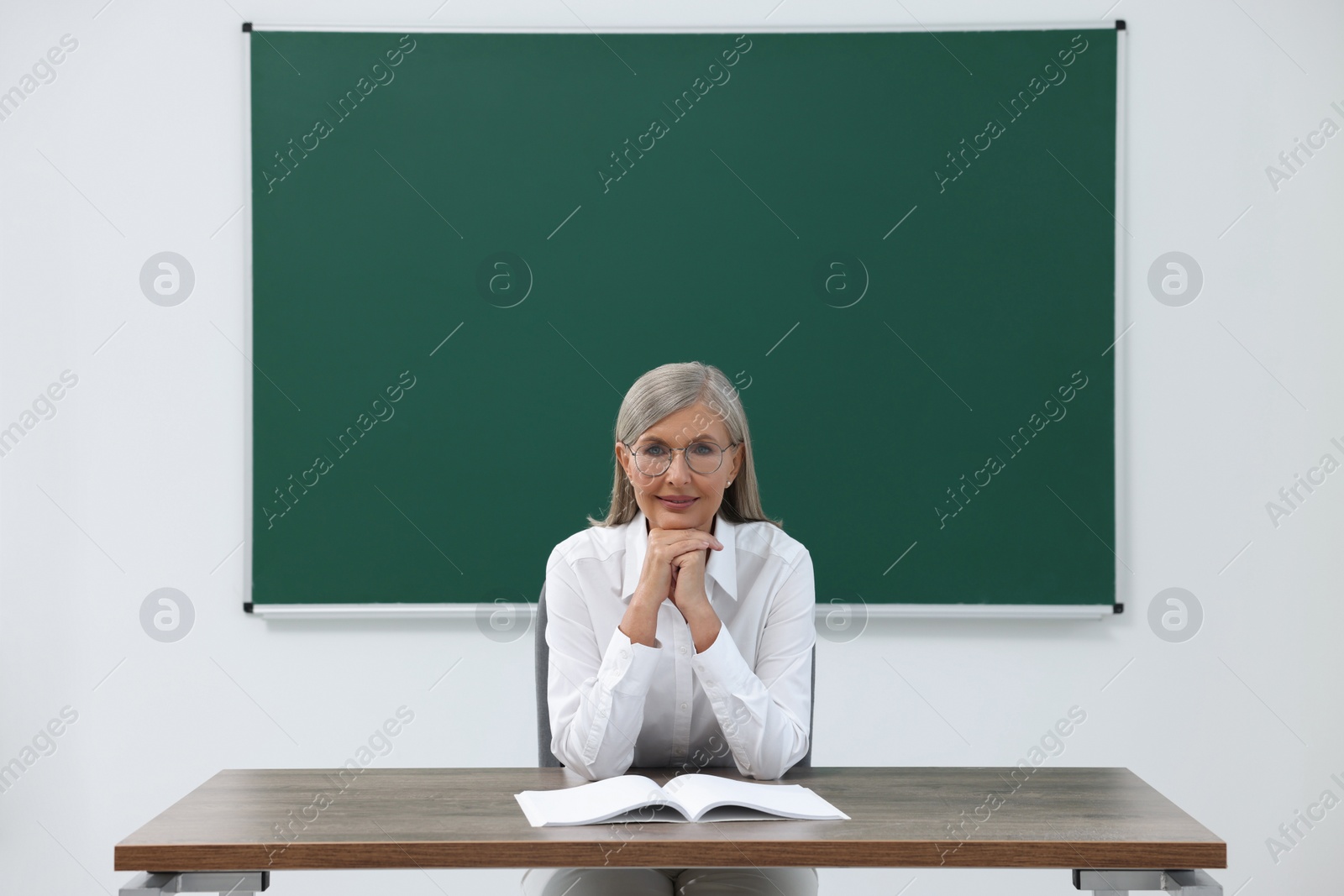 Photo of Portrait of professor sitting at desk in classroom