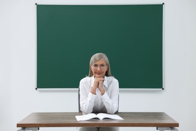 Portrait of professor sitting at desk in classroom