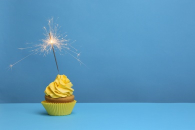 Photo of Birthday cupcake with sparkler on color background