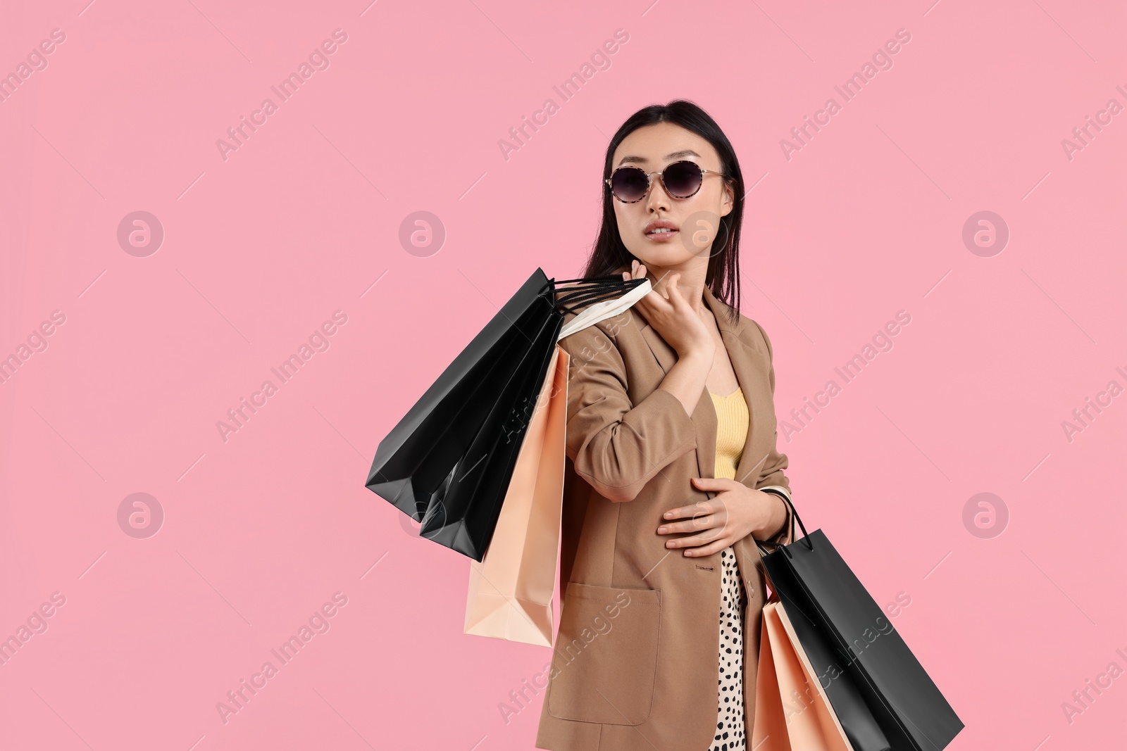 Photo of Beautiful woman with shopping bags on pink background. Space for text