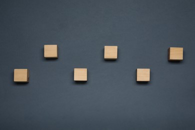 Blank wooden cubes on dark grey background, flat lay