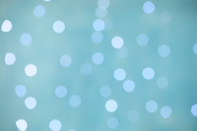 Photo of Blurred view of festive lights on light blue background. Bokeh effect