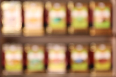 Blurred view of containers with different teas on rack in store