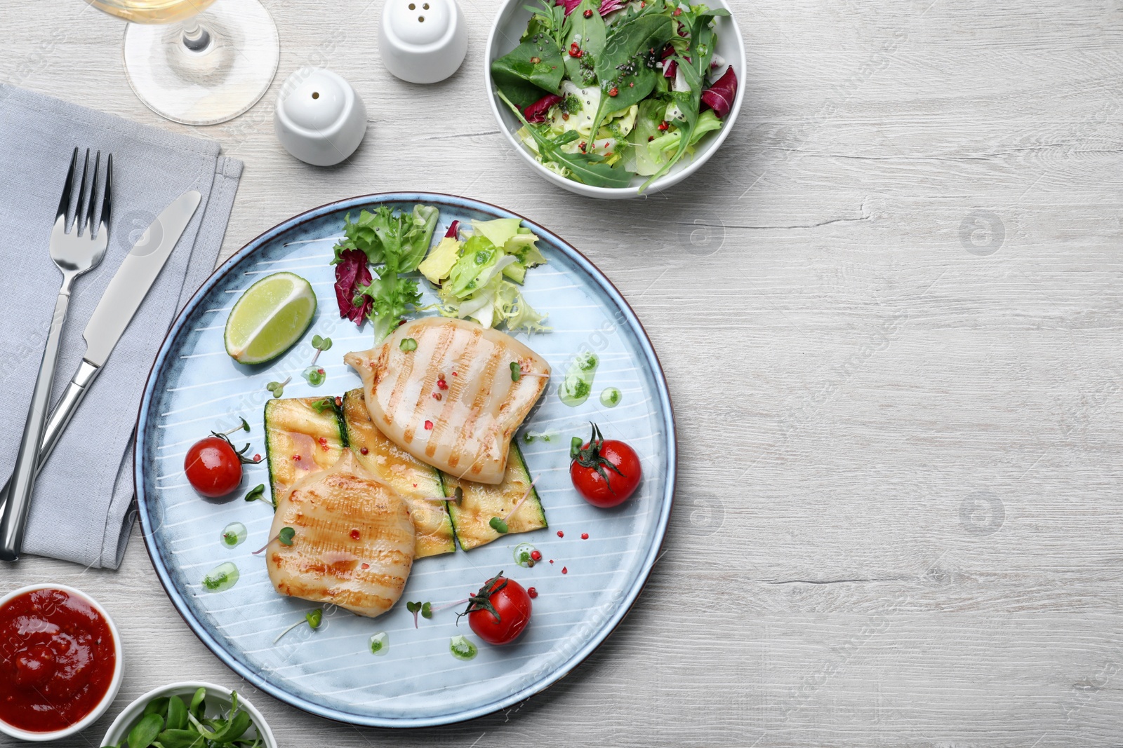 Photo of Grilled squid tubes served on white wooden table, flat lay. Space for text