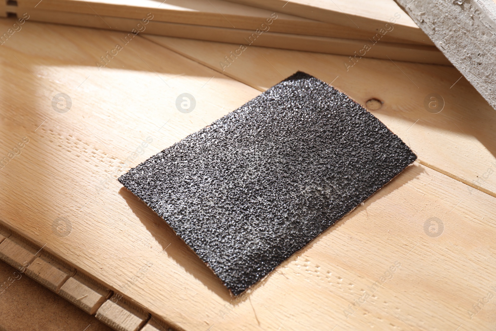 Photo of One coarse sandpaper on wooden planks, closeup