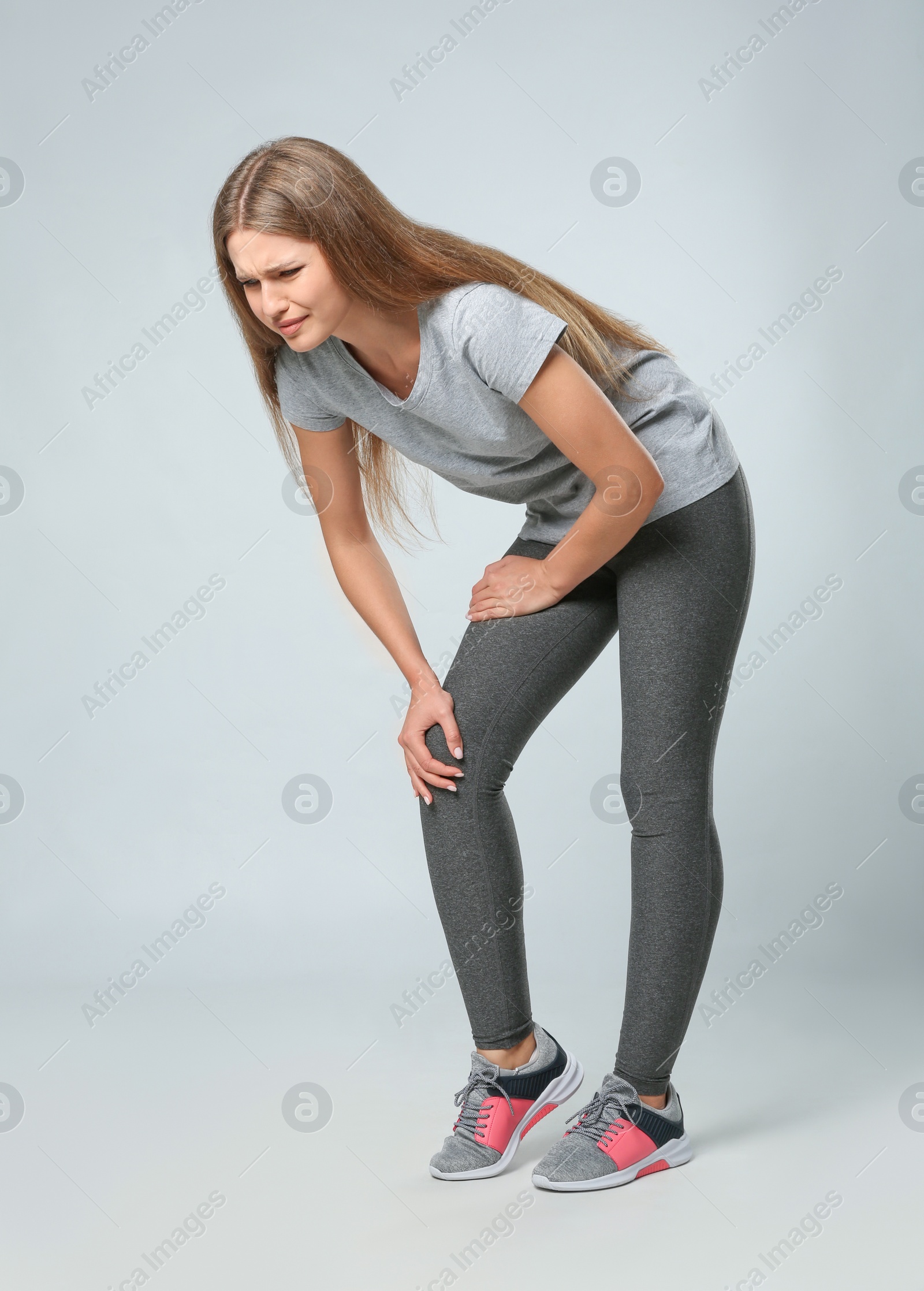 Photo of Full length portrait of sportswoman having knee problems on grey background