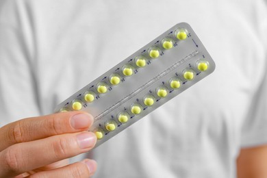 Photo of Woman holding blister with birth control pills, closeup