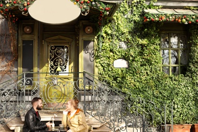 Lovely young couple enjoying tasty coffee at outdoor cafe