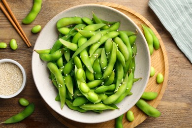 Green edamame beans in pods served with sesame seeds on wooden table, flat lay