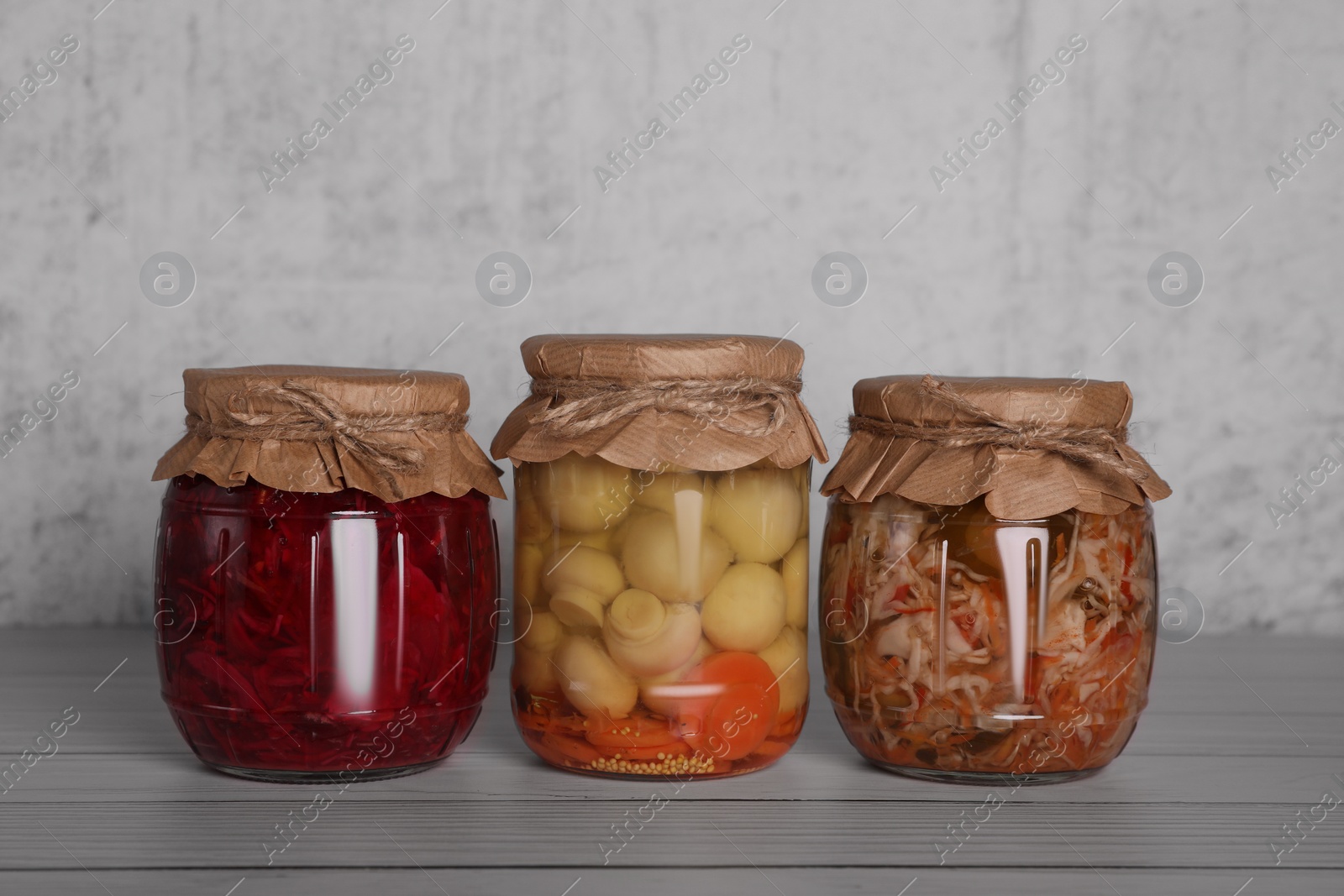Photo of Glass jars with different preserved vegetables and mushrooms on wooden table