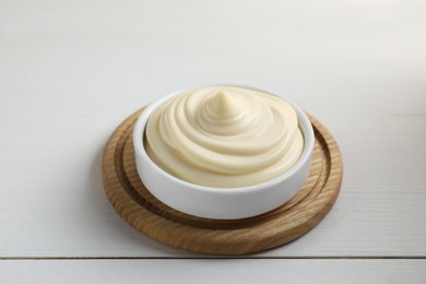 Photo of Fresh mayonnaise sauce in bowl on white wooden table