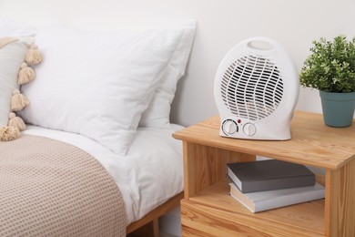 Modern electric fan heater on bedside table indoors