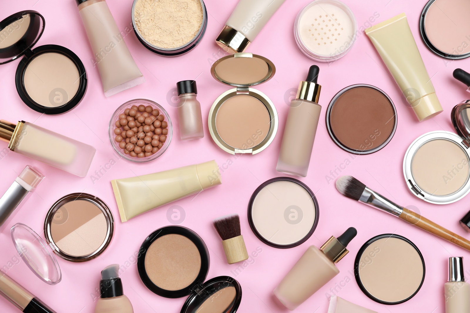 Photo of Face powders and other decorative cosmetic products on pink background, flat lay