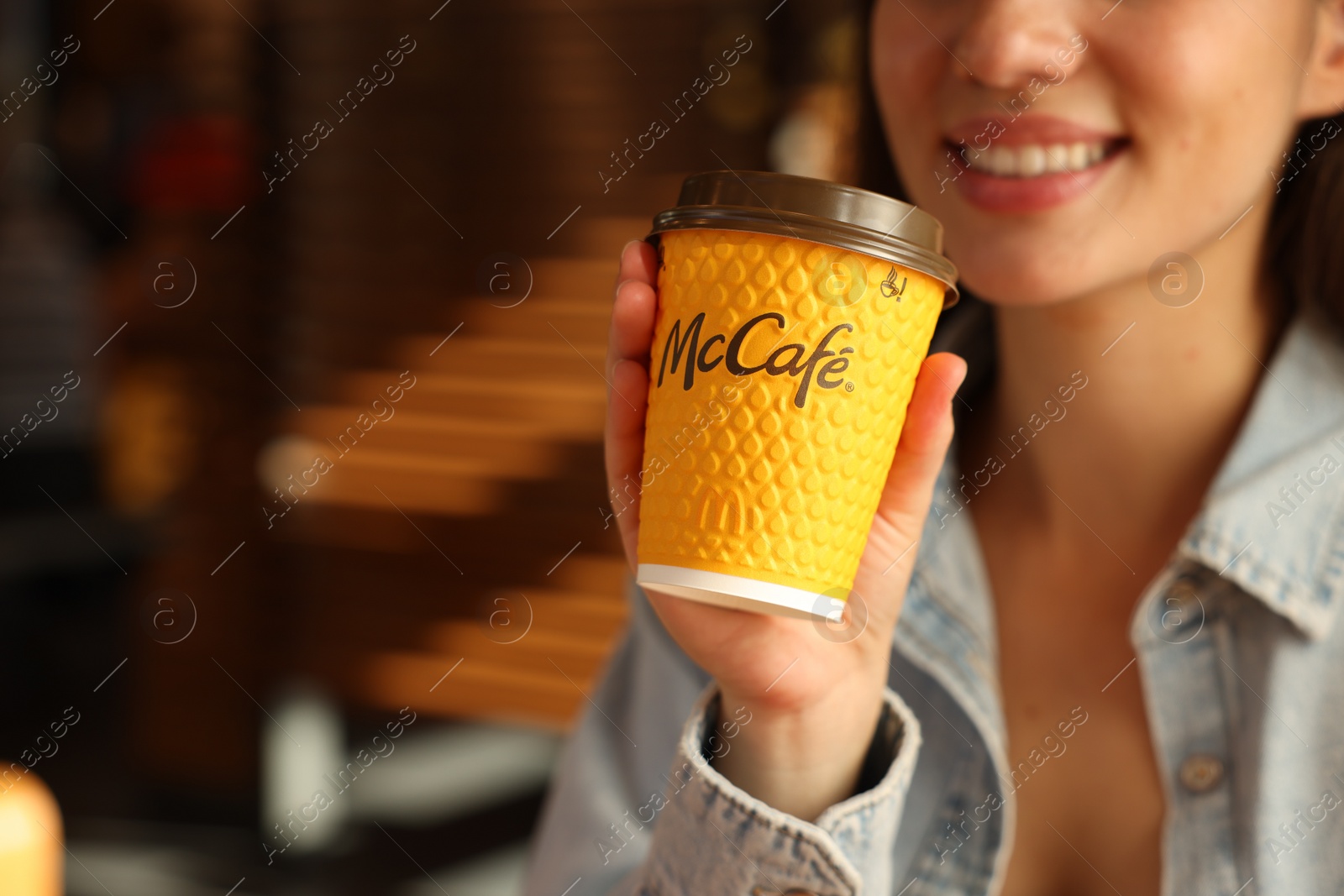 Photo of Lviv, Ukraine - September 26, 2023: Woman with hot McDonald's drink in cafe, closeup. Space for text