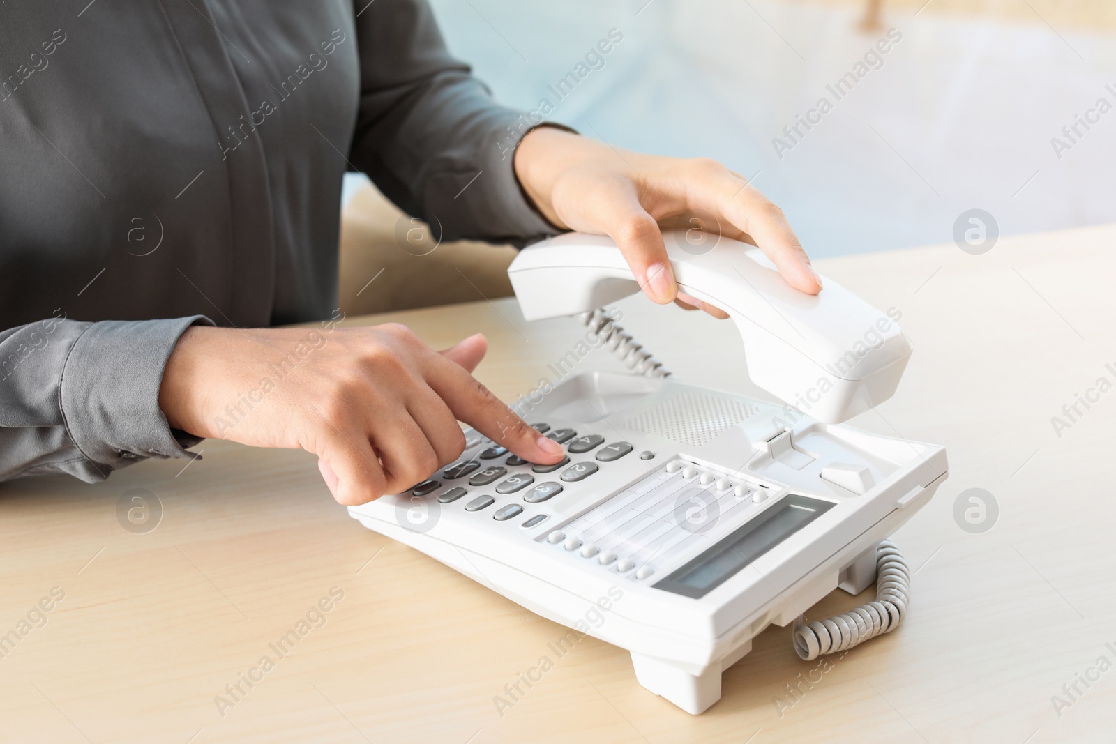 Photo of Woman dialing number on telephone at table in office