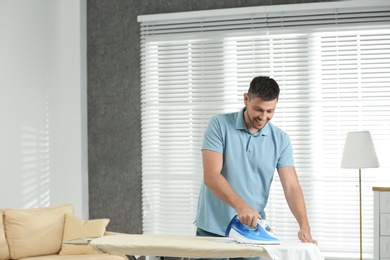 Photo of Handsome man ironing clean laundry at home