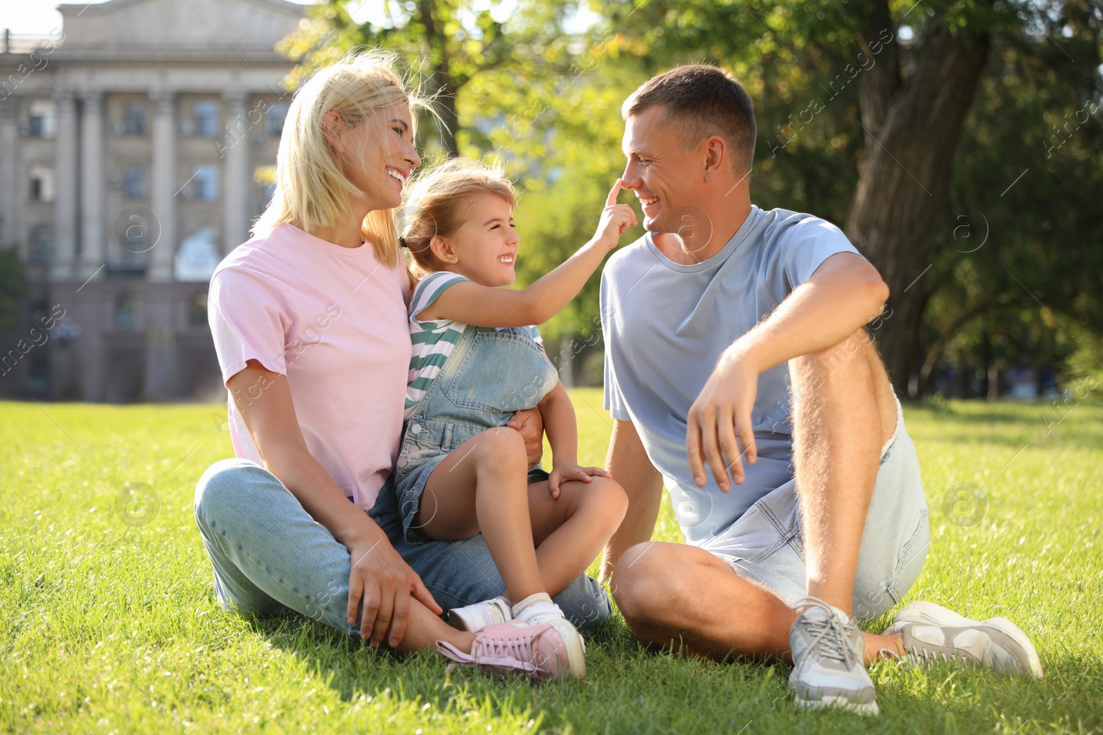 Photo of Happy parents with their child having fun on green grass. Spending time in nature