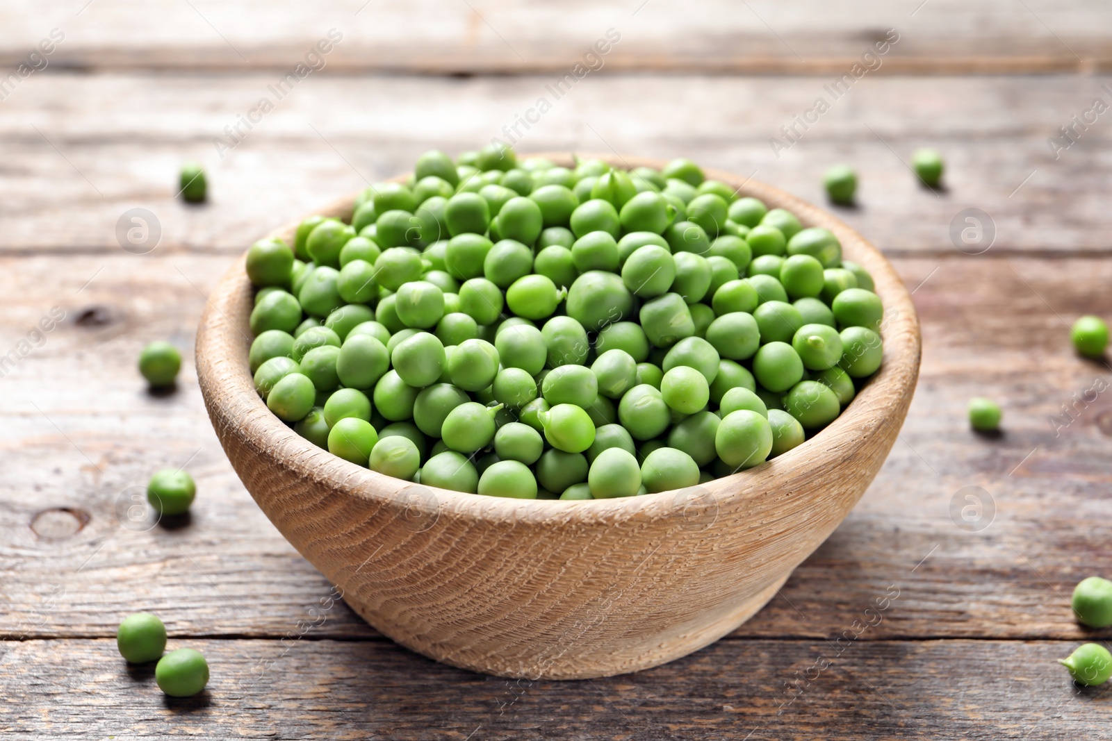 Photo of Bowl with delicious fresh green peas on wooden table