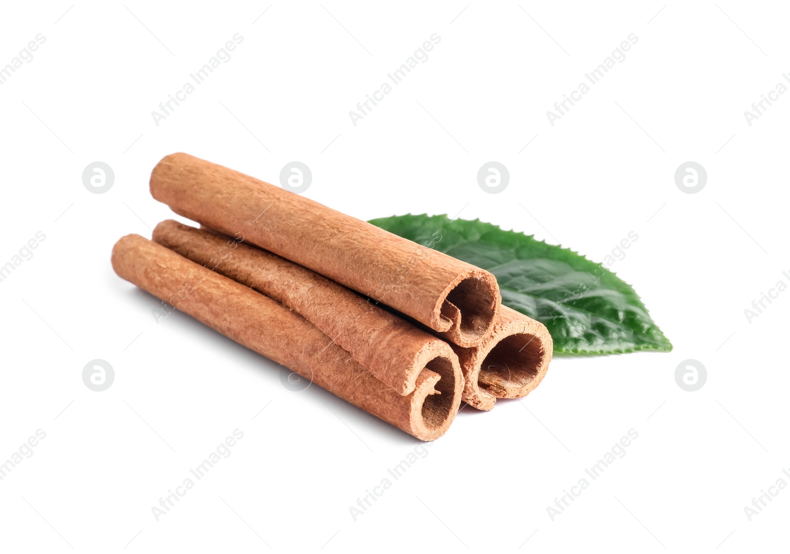 Photo of Aromatic cinnamon sticks and green leaf isolated on white