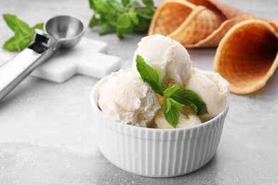 Delicious vanilla ice cream with mint on light grey table, closeup