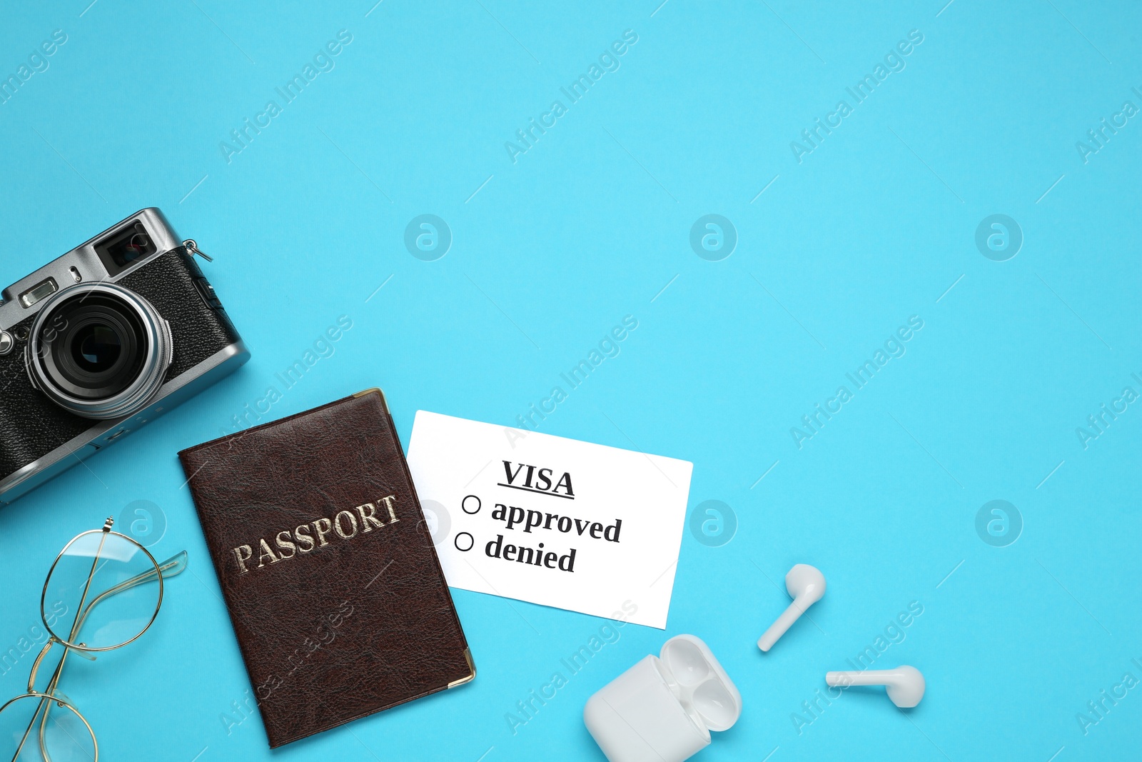 Photo of Flat lay composition with passport, camera and earphones on light blue background, space for text. Visa receiving