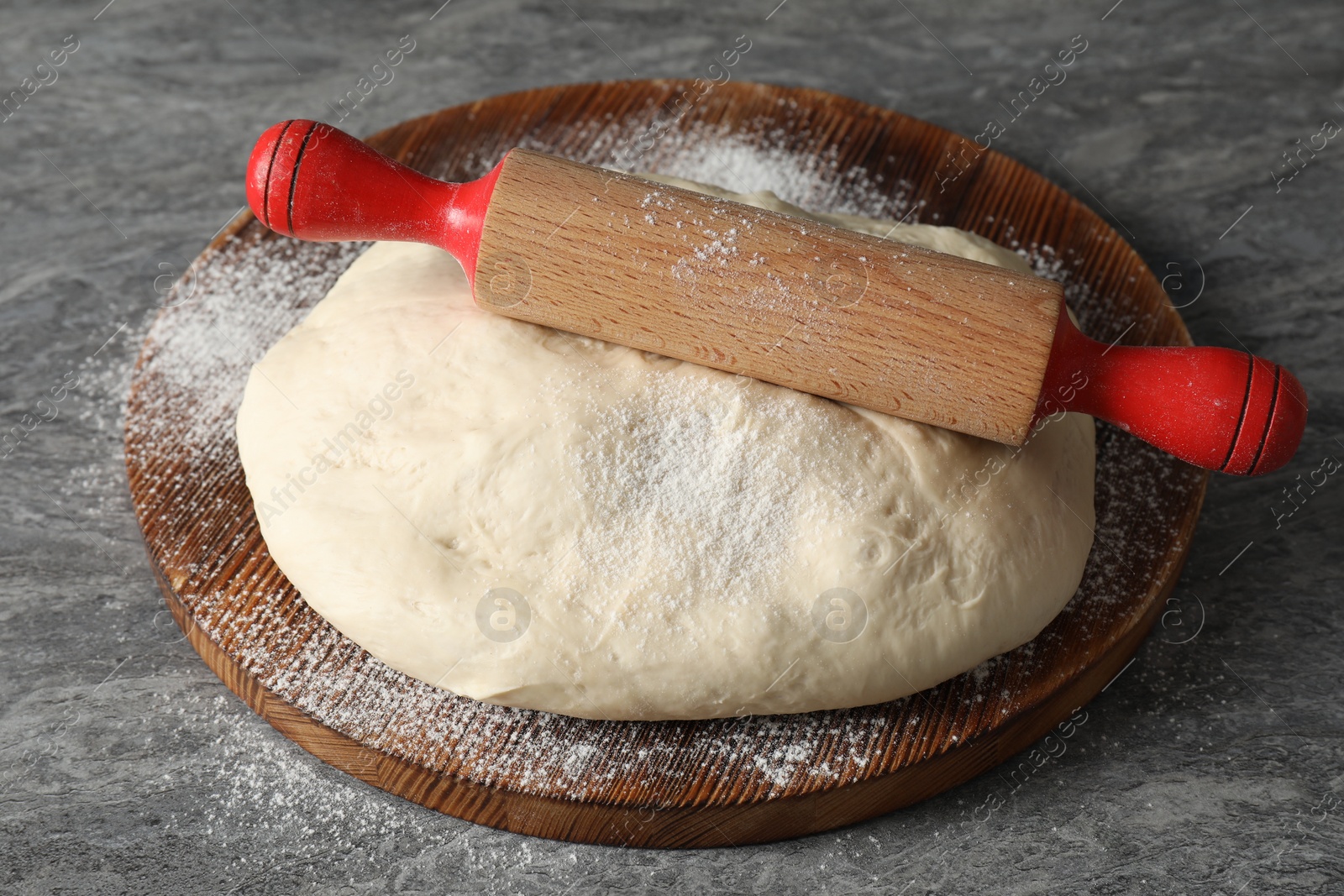 Photo of Raw dough and rolling pin on grey table