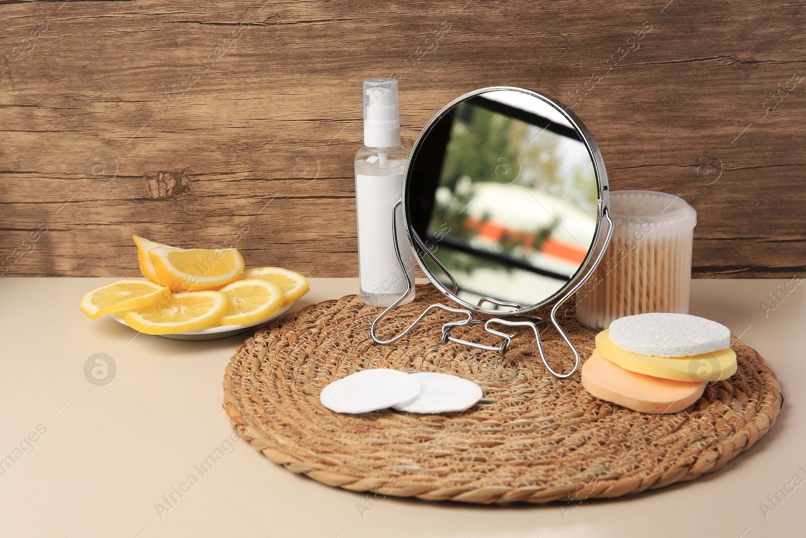 Photo of Lemon face cleanser. Fresh citrus fruits, personal care products and mirror on beige table