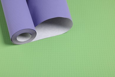 Image of One violet blue wallpaper roll on green background