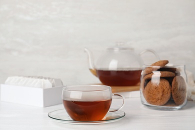 Photo of Cup of hot fresh tea and cookies on table against light background. Space for text