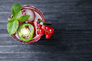 Photo of Spicy red currant cocktail with jalapeno and mint on black wooden table, top view. Space for text