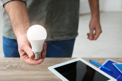 Photo of Man holding lamp bulb over table, closeup