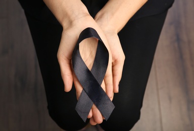 Photo of Woman holding black ribbon, closeup. Funeral symbol