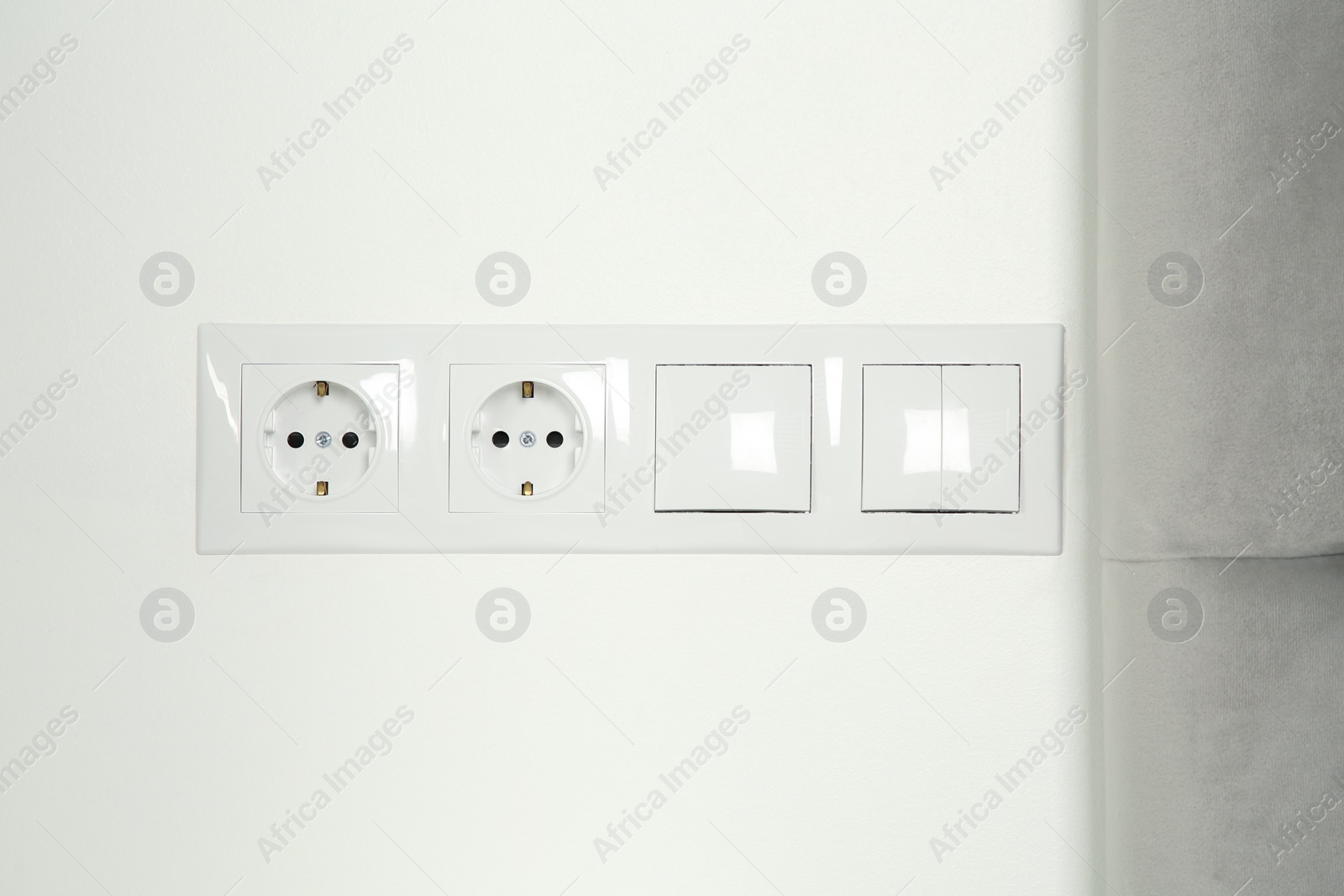 Photo of Light switches and power sockets on white wall indoors