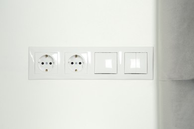 Light switches and power sockets on white wall indoors