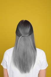 Image of Woman with gray hair on yellow background, back view