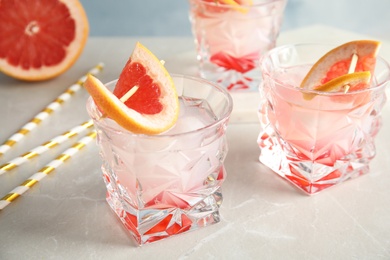 Photo of Glasses with tasty grapefruit cocktails on table