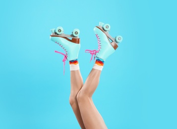 Photo of Young woman with retro roller skates on color background, closeup