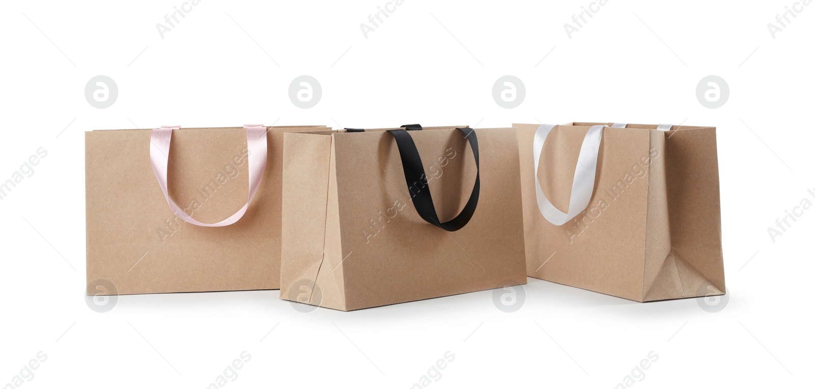 Photo of Paper shopping bags with ribbon handles on white background. Mockup for design