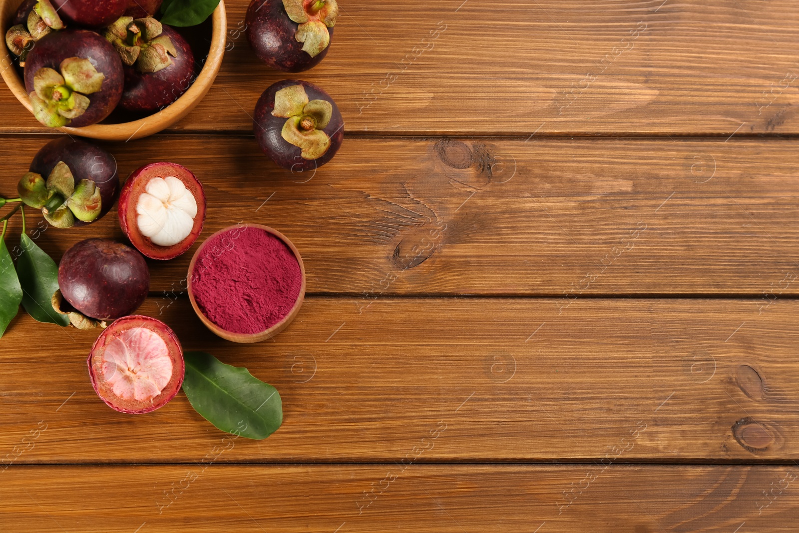 Photo of Purple mangosteen powder and fruits on wooden table, flat lay. Space for text